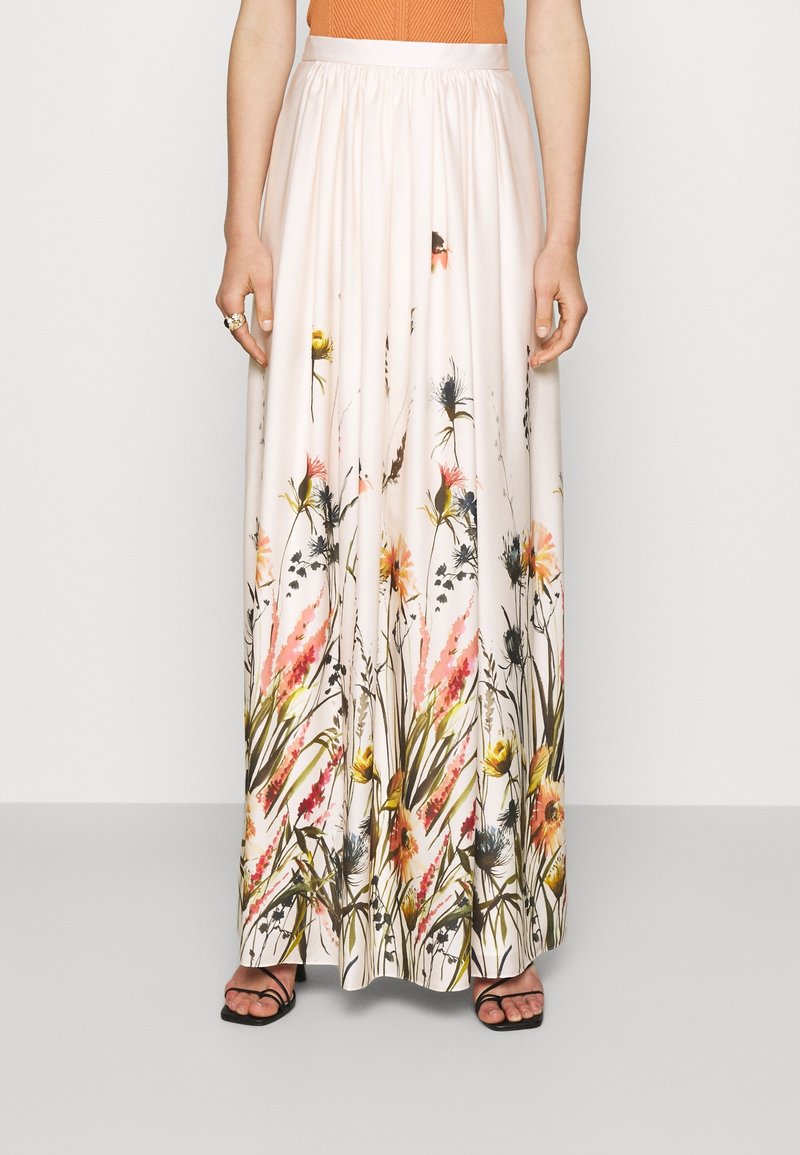 Blommig maxikjol i ljusrosa tyg med livliga blommönster i gult, orange och svart. Elastisk midjering för komfort.