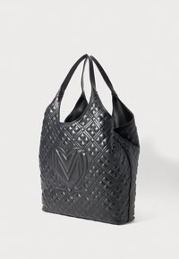 Black quilted leather handbag with double handles and embossed large logo on the front, shown against a plain white background.