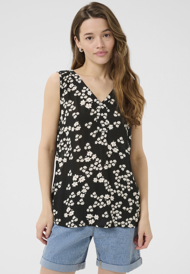 Haut sans manches floral noir avec décolleté en V, orné de fleurs blanches et roses, en tissu léger et à coupe décontractée, associé à un short en denim.