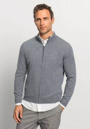Grauer Reißverschluss-Pullover aus weichem Stoff, mit hohem Kragen, langen Ärmeln und geradem Bund über einem weißen Shirt.