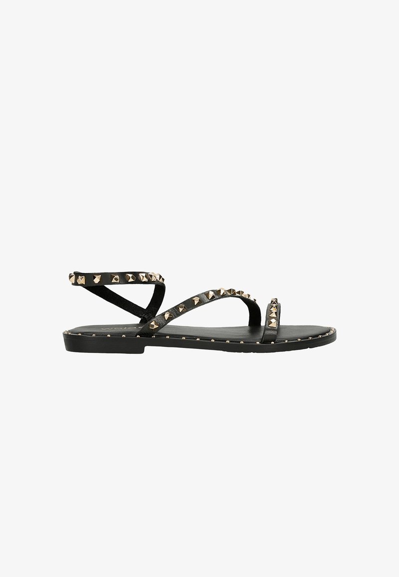 Schwarze flache Sandalen mit mehreren kreuzförmigen Riemen, die entlang der Riemen und der Sohle mit goldenen Metallnieten verziert sind. Hergestellt aus glattem Leder.