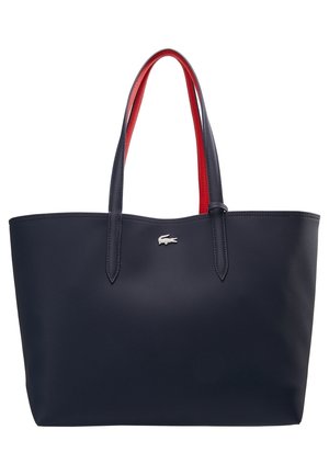 Grote navyblauwe shopper met rode binnenhandvatten en een klein zilveren krokodillenlogo middenvoor.