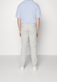 Ljusblå kortärmad t-shirt i kombination med ljusgrå slim-fit byxor. Byxorna har bakfickor; skorna har en strukturerad vit sula med rosa detaljer.