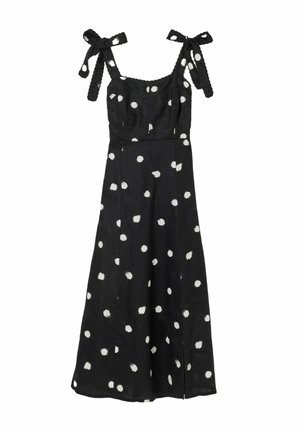 Schwarzes ärmelloses Kleid mit weißen Punkten, mit gebundenen Schulterträgern und einem fließenden, knielangen Rock.