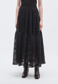 Μαύρη μακριά φούστα από δαντέλα με στρώματα και ελαστική μέση, με σχέδια σε όλη την επιφάνεια και ημιδιάφανο ύφασμα, συνδυασμένη με μποτάκια αστραγάλου.