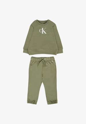 Felpa verde oliva con collo a giro e logo bianco, abbinata a pantaloni con cordoncino coordinati, dotati di polsini elasticizzati e tasche laterali.