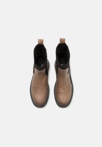 Paire de bottines Chelsea en cuir marron avec côtés élastiques noirs et languettes, vue de dessus sur un fond blanc uni.