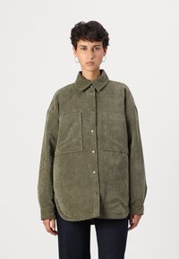 Camisa-jacket de corduroy verde com gola, fecho com bot�ões, dois bolsos no peito e um corte descontraído. Tecido texturizado e mangas longas.