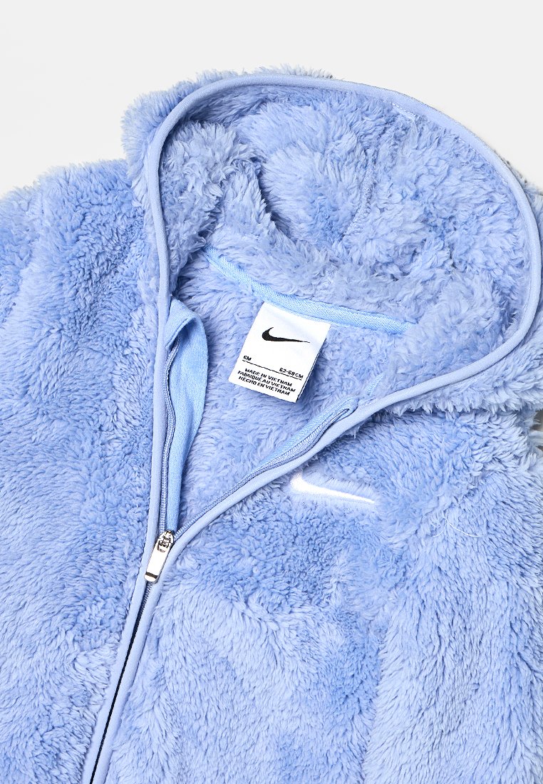 Sudadera con cremallera de felpa azul claro con una textura suave. Cuenta con capucha, cremallera en contraste y etiqueta del logo de Nike en el interior.