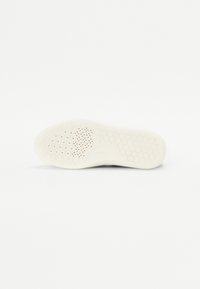 Suola di sneakers bianche con un pattern esagonale testurizzato e fori di ventilazione, dotata di una punta arrotondata e un bordo liscio.