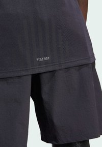 Black HEAT.RDY athletic top with textured fabric, featuring line patterns and a hem label. Paired with matching shorts in a similar texture.