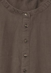 Camicia in corduroy marrone con scollatura rotonda e chiusura frontale con sette bottoni. Presenta una texture a coste verticali e dettagli con bottoni coordinati.