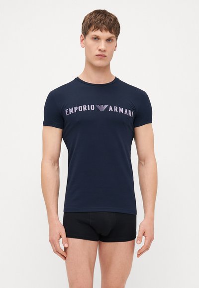 Mornarska majica s kratkim rukavima od mješavine pamuka, s "Emporio Armani" logom u svijetloplavoj boji preko prsa. Glatka tekstura.