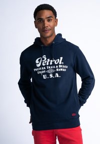 Navyblauwe hoodie met een zachte textuur, met witte tekst: "Petrol Polihua Trail & Beach Enjoy Hawaii U.S.A." Rode accenten aan de onderkant.