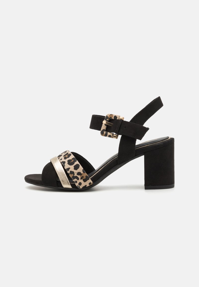 Sandale pour femmes en noir et imprimé léopard avec une sangle métallique dorée et un talon bloc. Présente une sangle de cheville réglable et une texture en daim douce.