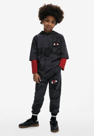 Hoodie graphique noir avec des manches longues rouges, associé à un jogging assorti. Présente un emblème de spider bien visible, fabriqué en tissu mélange coton.
