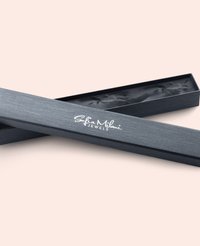 Grå smyckeskrin med en strukturerad yta och släta kanter. Har en vit logotyp "Sofia Milani JEWELS" på locket. Öppnat, vilket avslöjar en svart inredning.