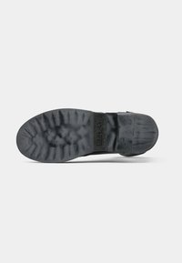 Sole of a black rubber boot with deep treads and the word "REPLAY" embossed near the heel section.