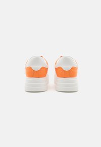 Sneakers with a white leather and orange suede upper, chunky white sole, and rounded heel. Soft texture with contrasting color accents.