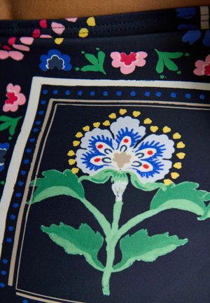 Tume kangas värvika lillemustriga, mille keskel on valge õis siniste, punaste ja kollaste detailidega ning seda ümbritsevad roosad ja sinised õied.