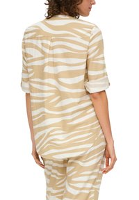 Beige Hemd mit weißen Zebra-Streifen, aus leichtem Stoff gefertigt. Hat einen lässigen Schnitt und hochgekrempelte Ärmel, sichtbare Rückennaht.