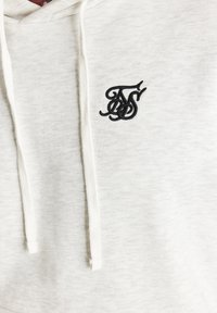 Felpa con cappuccio grigio chiaro dal tessuto morbido, con un logo ricamato nero sul petto e dettagli in bianco sui lacci.