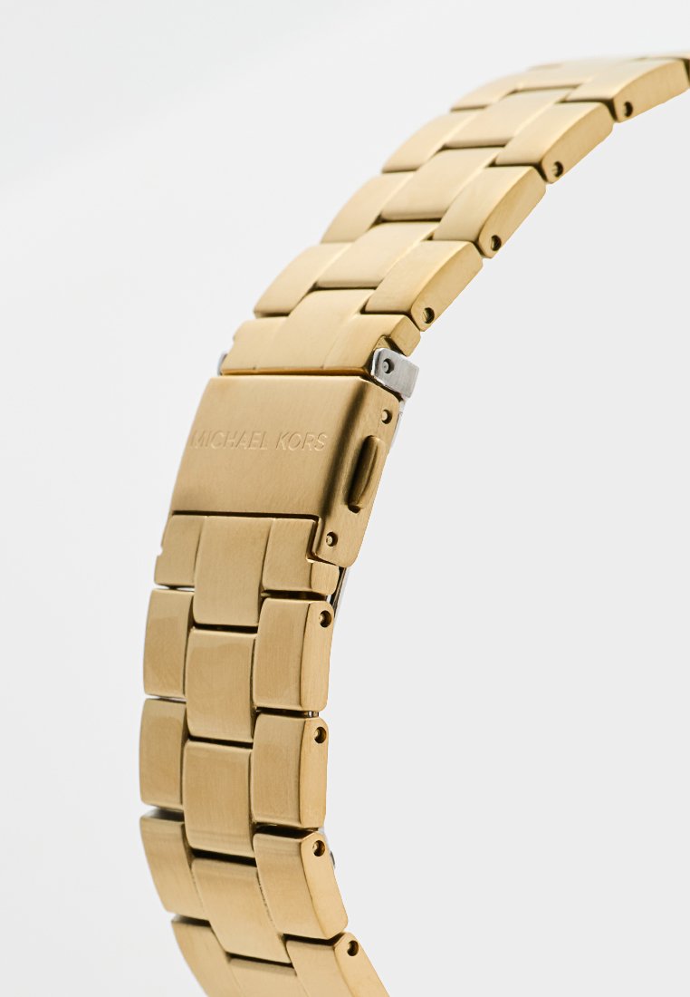 Bracelet de montre en métal doré avec maillons, présentant une texture lisse et une finition brossée. Comprend un fermoir avec un logo gravé.