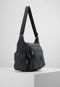 Borsa a spalla in tessuto grigio scuro con molteplici scomparti con zip e una larga tracolla regolabile con cuciture bianche.