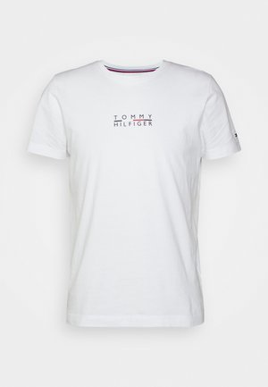 T-shirt blanc en coton manches courtes avec texte "Tommy Hilfiger" en noir et rouge centré sur la poitrine, col rond avec un subtil détail rayé à l’intérieur.