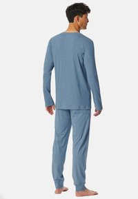 Blauw pyjama-overhemd met lange mouwen en bijpassende broek, gemaakt van zacht materiaal. Eenvoudig ontwerp met ribgebreide manchetten, losse pasvorm en geen zichtbare patronen.
