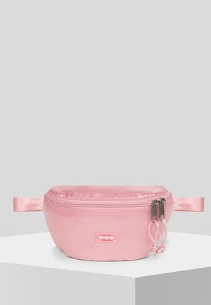 Mała różowa satynowa saszetka z podwójnym zamkiem błyskawicznym i dwoma bocznymi paskami, umieszczona na białym piedestale na jasnoszarym tle.