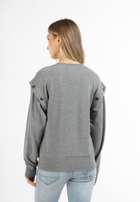 Grijze sweatshirt met lange mouwen, voorzien van knoopaccenten op de schouders en een geribbelde zoom. Gemaakt van zachte stof met een relaxte pasvorm.