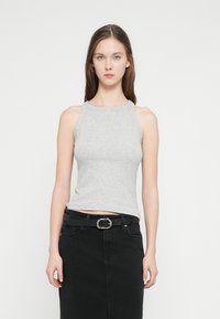 Ανοιχτό γκρι αμάνικη μπλούζα σε εφαρμοστή γραμμή, κατασκευασμένη από ριμπ βαμβακερό μείγμα, συνδυασμένη με μαύρη φούστα τζιν και ζώνη με ασημένια αγκράφα.