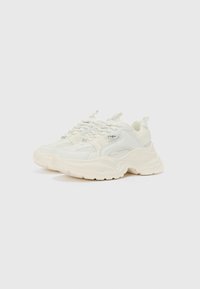 Chunky white sneakers featuring a mix of smooth and textured materials, prominent lacing system, and rounded sole design.