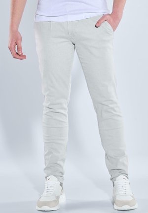 Light gray, slim-fit pants with a smooth texture, featuring side pockets and subtle front pleats. Paired with white and beige sneakers.