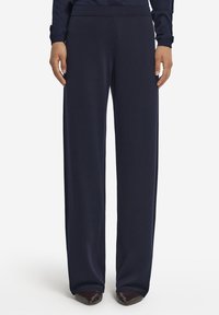 Navyblå vida byxor i mjukt tyg med elastisk midja. Sömmen är avslutad med en slät kant, vilket kompletterar den flödande designen.