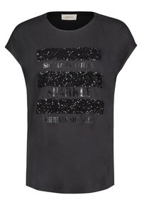 T-shirt gris à manches courtes, avec un design en sequins et en texte métallique qui indique "ELLE LAISSE UN PETIT ÉCLAT PARTOUT OÙ ELLE VA."