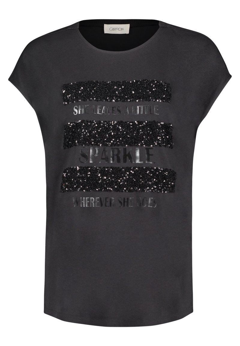 T-shirt gris à manches courtes, avec un design en sequins et en texte métallique qui indique "ELLE LAISSE UN PETIT ÉCLAT PARTOUT OÙ ELLE VA."