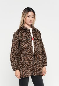 Giacca in stampa leopardata realizzata in tessuto morbido, con chiusura a bottoni, due tasche sul petto e una vestibilità rilassata. I colori disponibili sono marrone, nero e sabbia.