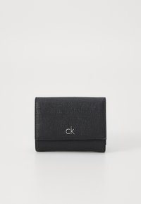 Svarte skinnlommebok med en teksturert overflate, som har en sølvfarget "ck"-logo på forsiden og en klaffdesign.