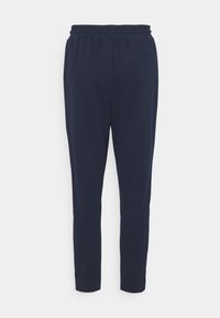 Pantalon bleu marine fuselé avec une taille élastique et une seule poche arrière, présenté de dos sur un fond blanc.