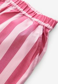 Tissu rayé rose avec des nuances alternées de rose clair et foncé. Taille élastique avec texture froncée. Matière en coton lisse.