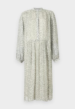 Dolga svetlo zelena obleka z vzorcem leopardjega tiska. Ima gumbe spredaj, nabran pas in dolge rokave z elastičnimi manšetami.