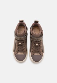 Sneaker alte marroni con upper testurizzato, hardware dorato e chiusura a cinturino. Presentano un collare imbottito e una punta di colore contrastante.