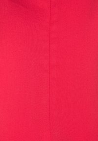 Surface en tissu rouge vif avec une couture verticale centrale, montrant une légère texture et des coutures régulières.