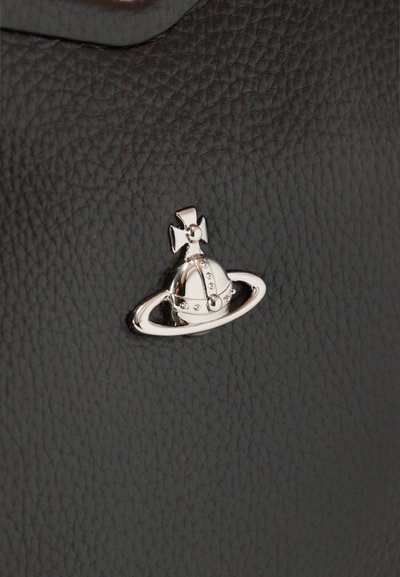 Ασημένια σφαίρα με έμβλημα σταυρού και δακτυλίου σε υφή μαύρου δέρματος, στο κέντρο και σε κοντινή απόσταση.