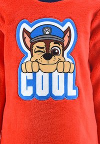 Red fleece sweatshirt featuring a cartoon dog wearing a blue cap, winking with paws on the word "COOL" in bold blue and white letters.