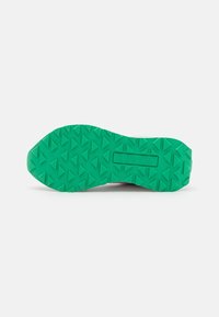 Green rubber outsole with a textured, triangular tread pattern; features brand name imprint. Smooth transition to a pink upper (not visible).