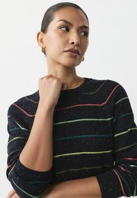 Marineblå sweater med flerfarvede striber, strukturerede prikker og rund hals. Den har ribstrikkede manchetter og en afslappet pasform.