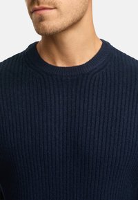 Granatowy sweter z prążkowanej dzianiny o okrągłym dekolcie, teksturowanej powierzchni i subtelnych poziomych liniami. Brak widocznych zdobień lub akcentów.